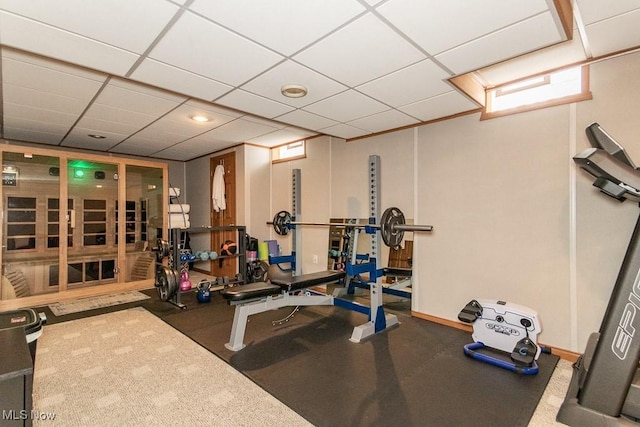 workout room featuring a paneled ceiling and baseboards