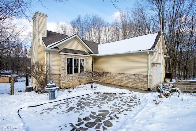 view of front of property featuring stone siding, a chimney, and central AC unit