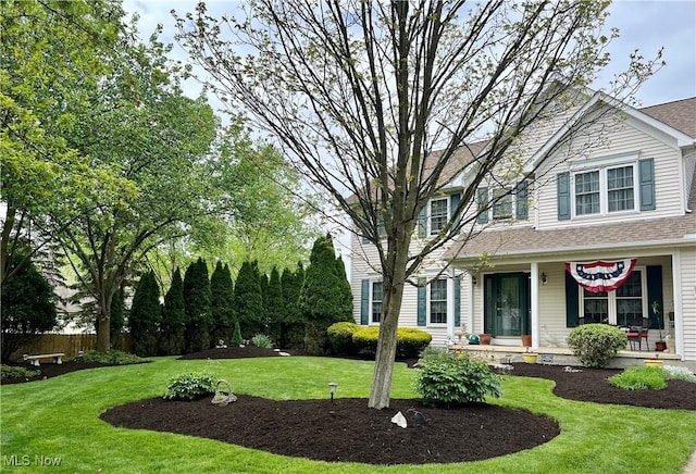 view of front facade featuring a front lawn, fence, and roof with shingles