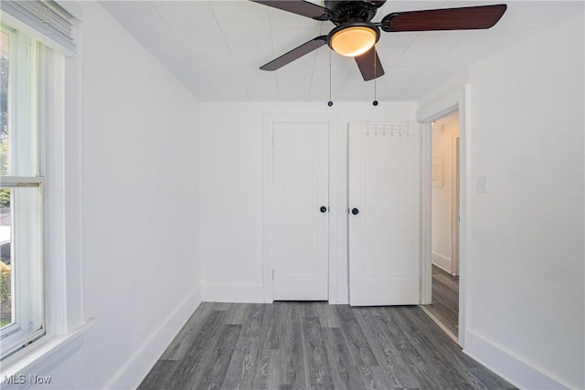 unfurnished bedroom featuring ceiling fan, a closet, baseboards, and dark wood-style flooring