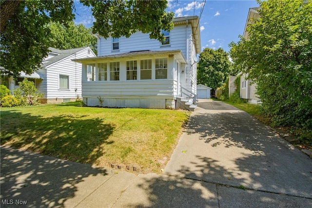 view of front of property featuring a garage, a front lawn, and an outdoor structure