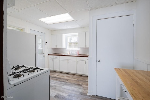 kitchen with butcher block countertops, white appliances, white cabinets, light wood finished floors, and tasteful backsplash