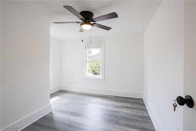 empty room featuring a ceiling fan, dark wood finished floors, and baseboards