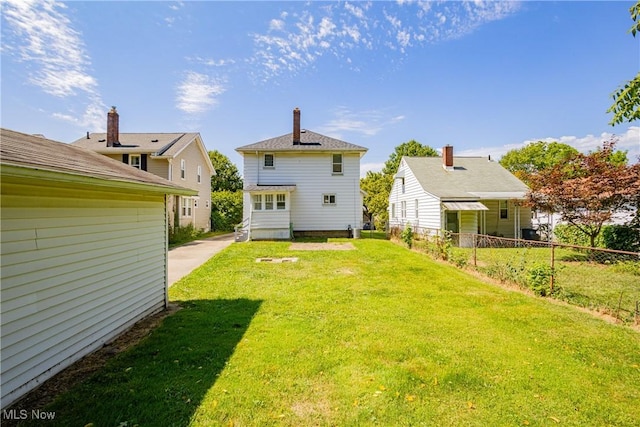 back of house featuring a lawn and fence