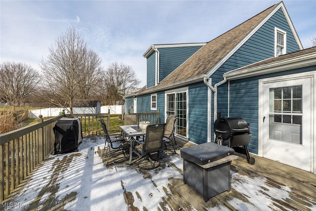 snow covered deck with outdoor dining space and grilling area