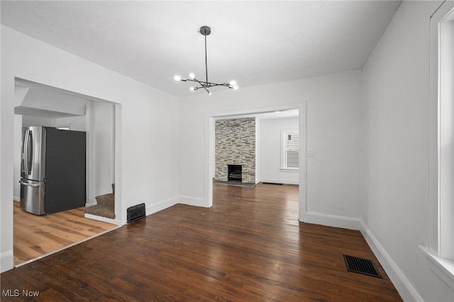 unfurnished dining area with dark wood-style floors, a fireplace, and visible vents