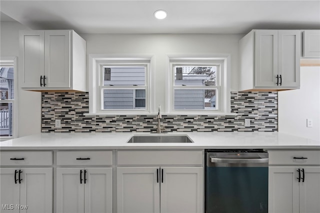 kitchen featuring white cabinets, light countertops, dishwasher, and a sink