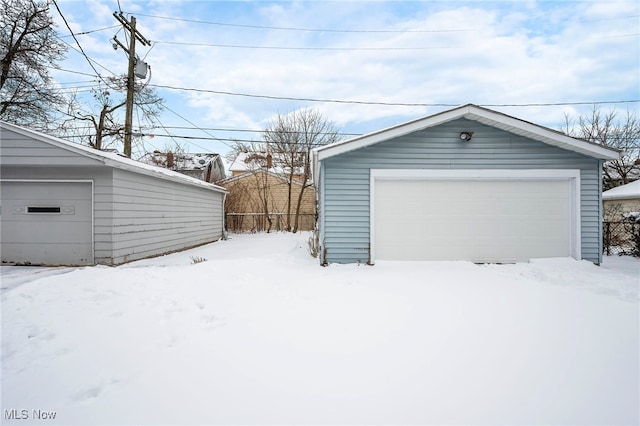 snow covered garage with a garage and fence