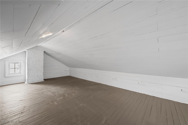 bonus room featuring vaulted ceiling, wood walls, and wood finished floors