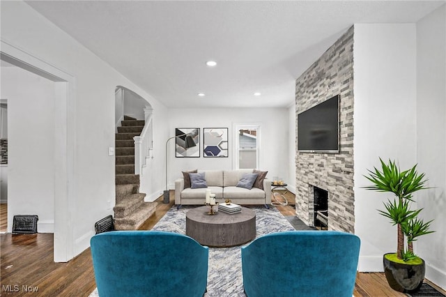 living room with recessed lighting, a fireplace, wood finished floors, baseboards, and stairs