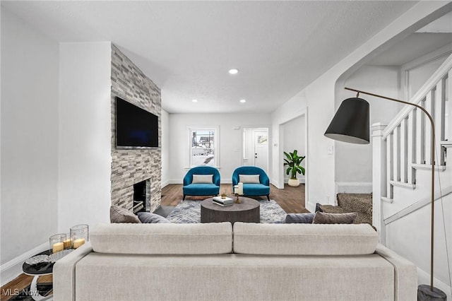 living area with recessed lighting, a fireplace, wood finished floors, baseboards, and stairway