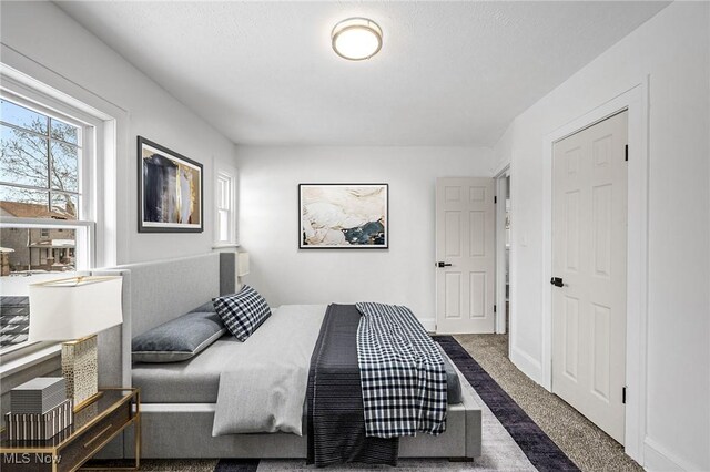 bedroom featuring dark carpet and baseboards