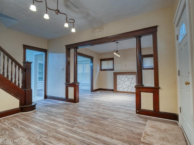 entrance foyer with light wood finished floors, decorative columns, stairs, and baseboards