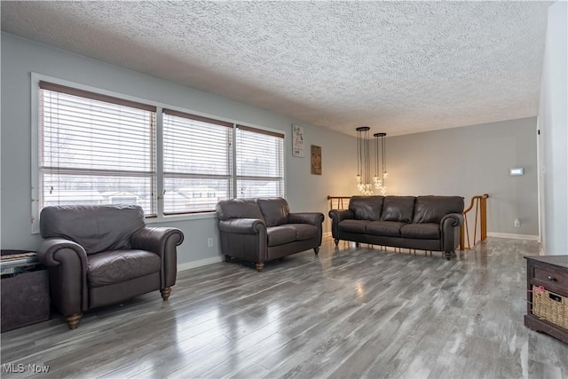 living room with a textured ceiling, baseboards, and wood finished floors