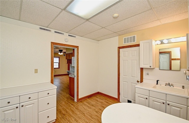 bathroom featuring visible vents, baseboards, a paneled ceiling, vanity, and wood finished floors