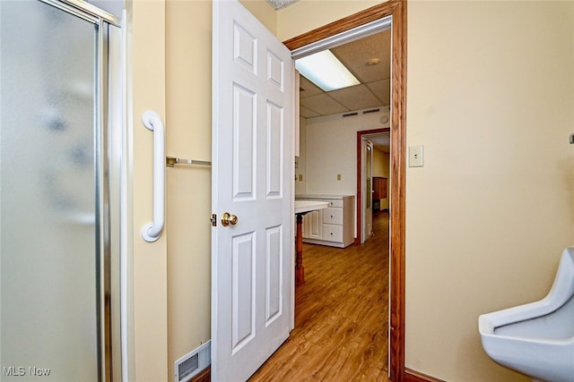 corridor with light wood-type flooring, visible vents, and a drop ceiling