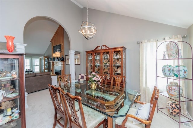 dining room featuring arched walkways, light colored carpet, a fireplace, an inviting chandelier, and ornate columns