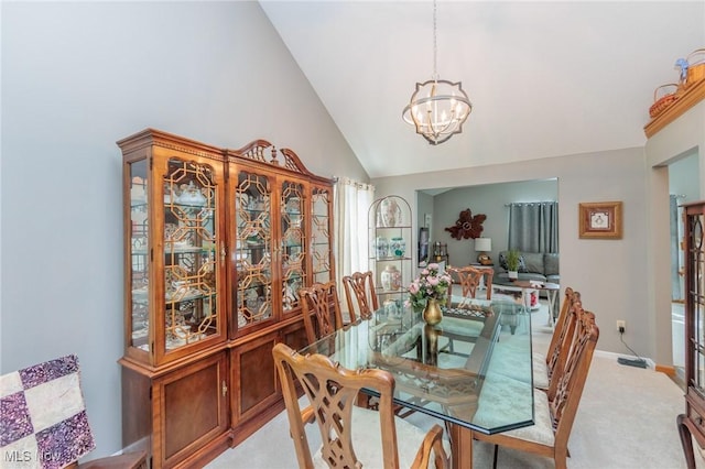 dining room featuring an inviting chandelier, high vaulted ceiling, and light colored carpet