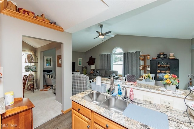 kitchen with vaulted ceiling, ceiling fan, open floor plan, and a sink