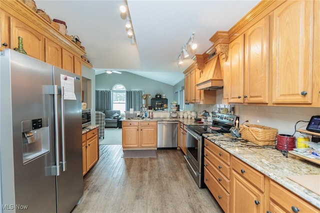 kitchen featuring light wood finished floors, stainless steel appliances, vaulted ceiling, ceiling fan, and premium range hood