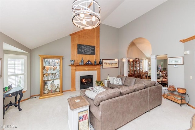 living area featuring light carpet, decorative columns, arched walkways, an inviting chandelier, and a fireplace