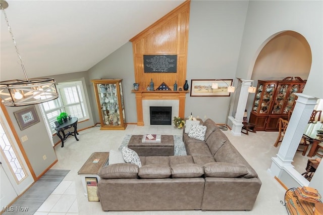 living area featuring high vaulted ceiling, arched walkways, ornate columns, and a tiled fireplace