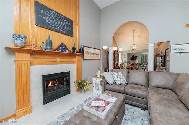 living area with decorative columns, vaulted ceiling, and a tile fireplace