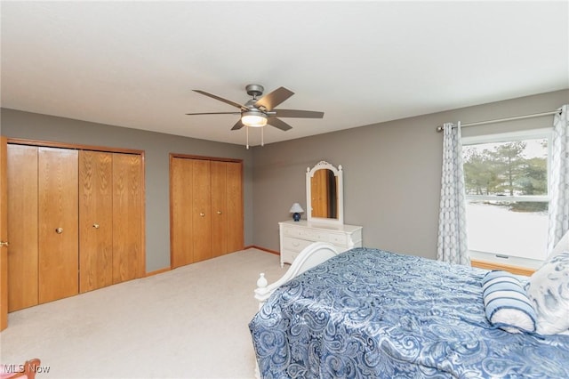 bedroom featuring carpet, a ceiling fan, and multiple closets