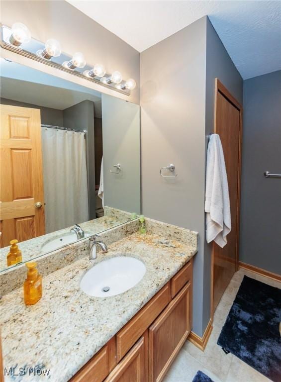 full bathroom with a shower with shower curtain, baseboards, and vanity