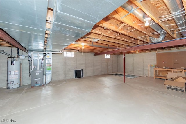 basement featuring water heater, brick wall, and heating unit