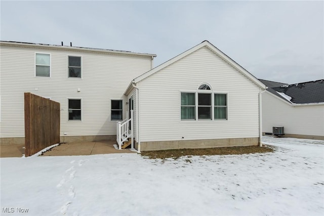 snow covered house featuring entry steps and central AC