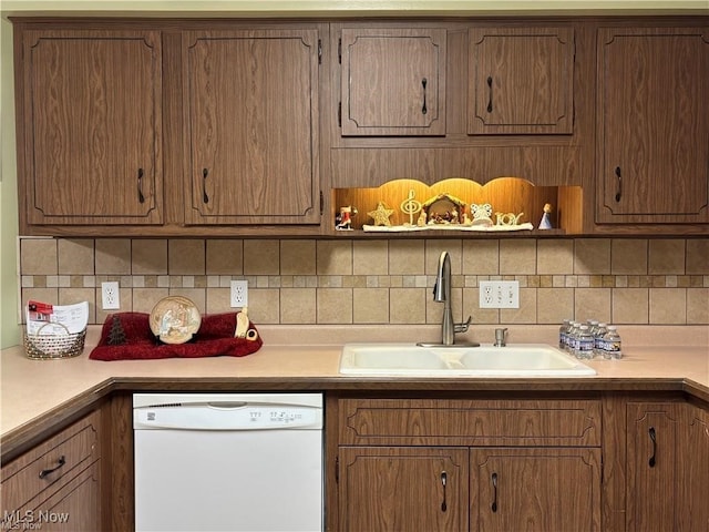 kitchen with tasteful backsplash, dishwasher, brown cabinets, light countertops, and a sink