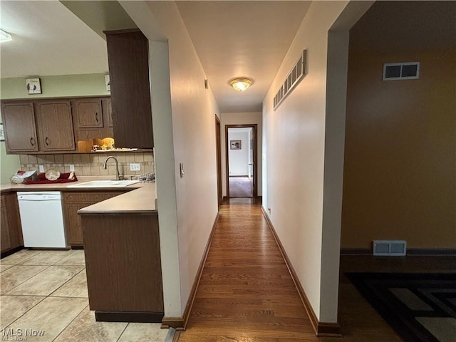 corridor featuring baseboards, visible vents, and a sink