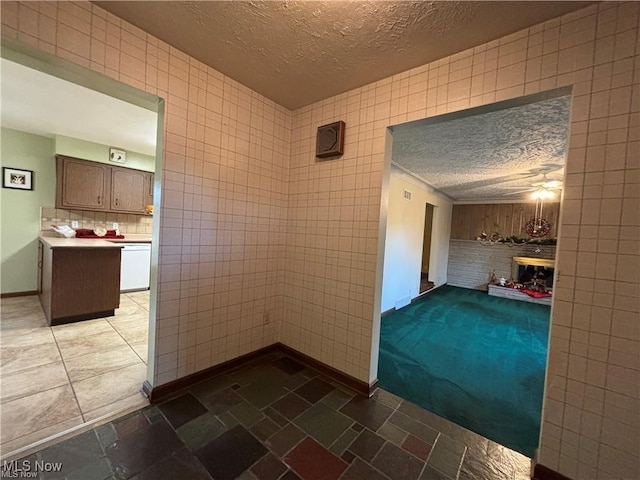 interior space featuring baseboards, a fireplace, tile walls, and a textured ceiling