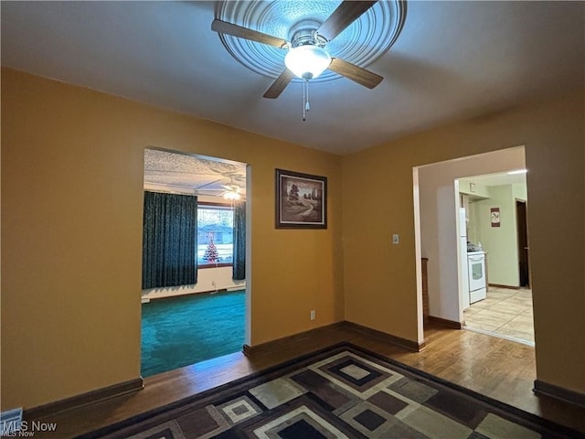 unfurnished room with baseboards, a ceiling fan, and wood finished floors