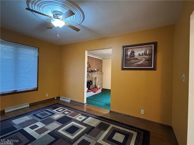 unfurnished room with ceiling fan, a brick fireplace, visible vents, and baseboards