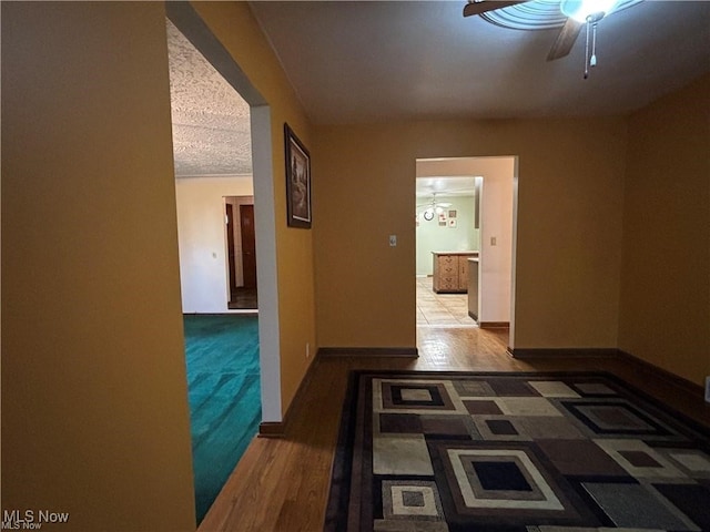 corridor with baseboards, arched walkways, and wood finished floors