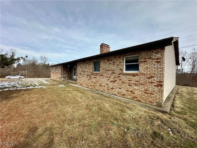 rear view of house featuring a yard, brick siding, and a chimney