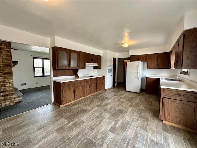 kitchen with dark brown cabinetry, white appliances, visible vents, light countertops, and under cabinet range hood