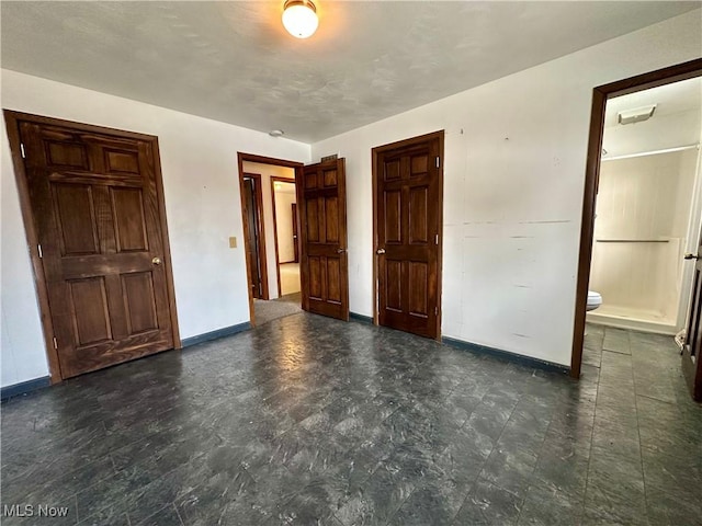 unfurnished bedroom featuring baseboards and connected bathroom