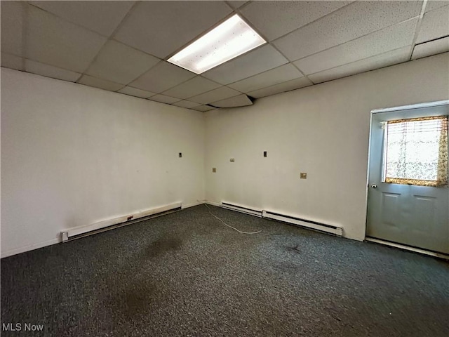 empty room featuring a paneled ceiling and baseboard heating