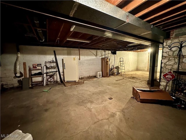 unfinished below grade area featuring freestanding refrigerator and water heater