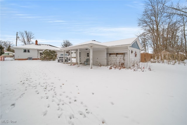 snow covered house featuring a porch and fence