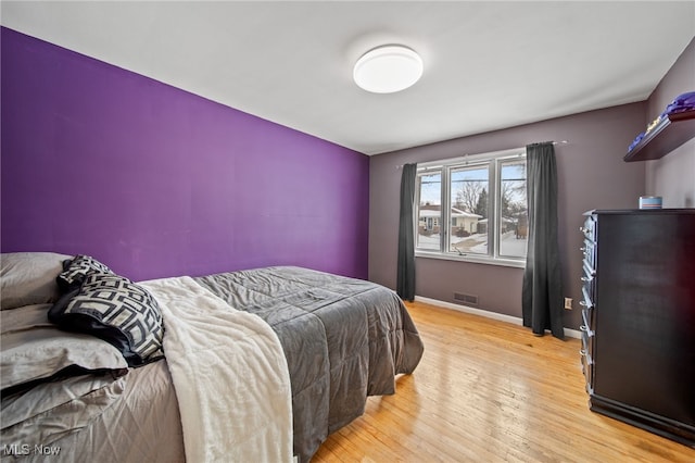 bedroom featuring light wood-style floors, visible vents, and baseboards