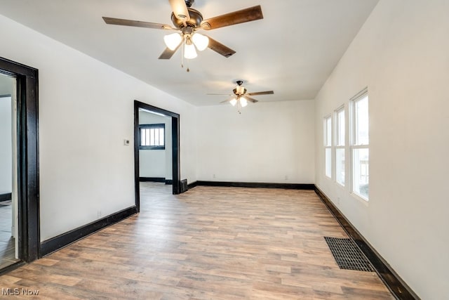 unfurnished room with light wood finished floors, visible vents, and baseboards