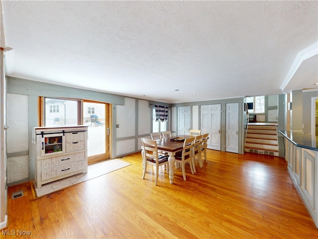 dining room featuring light wood-style flooring, visible vents, stairway, and a textured ceiling