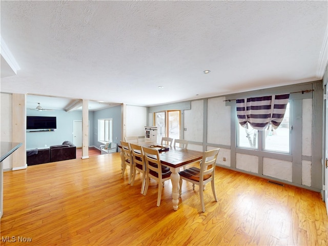 dining area with a textured ceiling, visible vents, a wealth of natural light, and light wood-style floors