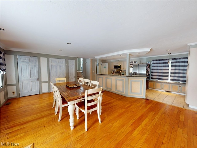 dining space with stairway, light wood-type flooring, visible vents, and crown molding