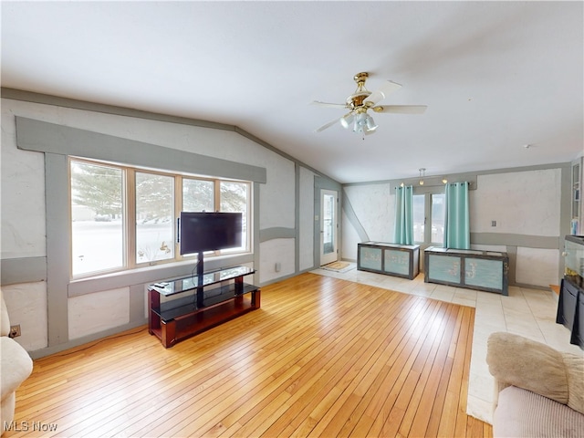 living area with a ceiling fan, lofted ceiling, and light wood finished floors