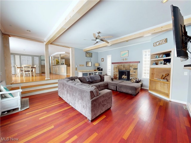 living area featuring beam ceiling, baseboards, a fireplace, and wood finished floors